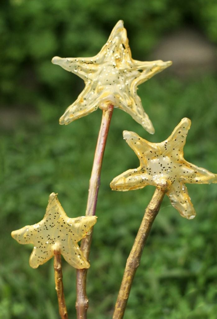 Sleepover Games and activities- Image shows a background of green grass and a stick with a star on top made of hot glue and gold paint and glitter from Kids Activities Blog.