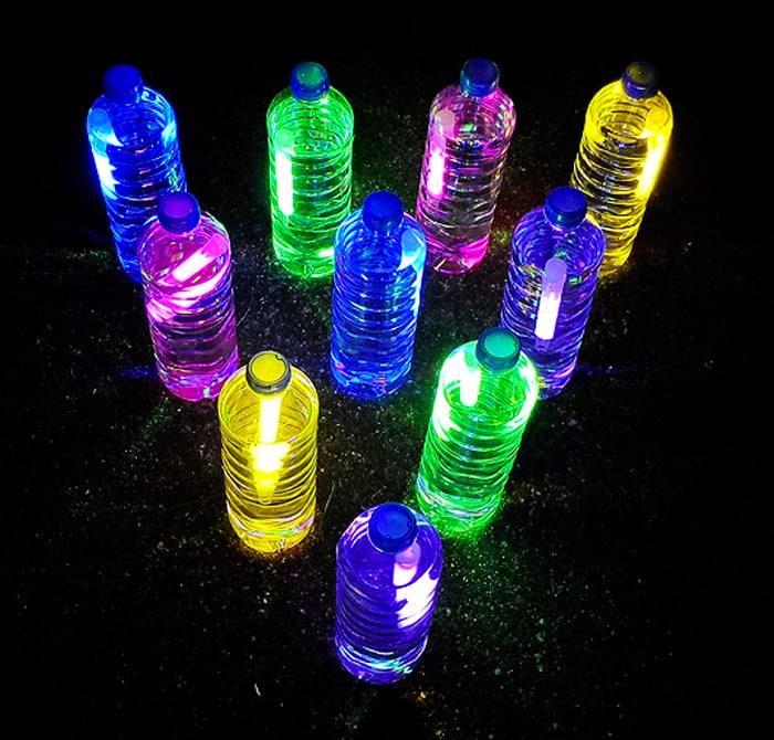 Sleepover Games and activities- Image shows a black background and water bottles with the contents of glow sticks porured in them to glow from Kix Cereal.